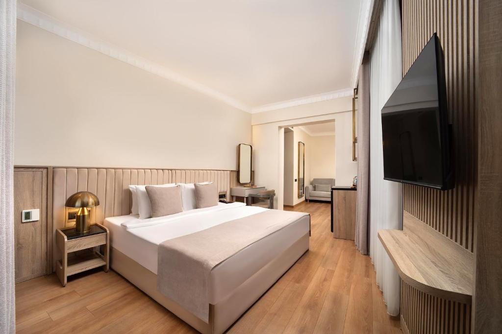 a bedroom with a white bed and a flat screen tv at Atik Hotel Nişantaşı in Istanbul