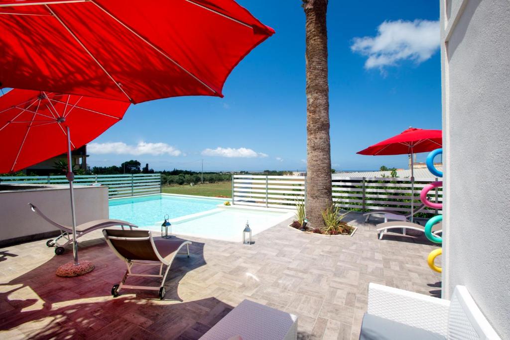 里里耶沃的住宿－La Rocca Scavata，一个带红色遮阳伞和游泳池的庭院