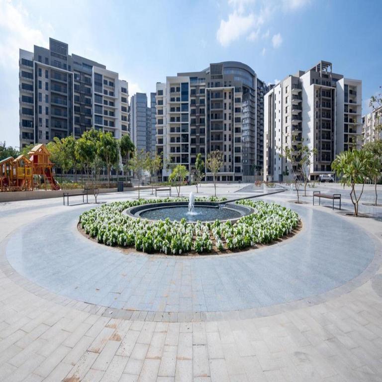 a fountain in the middle of a park with buildings at Habitat Towers in Sheikh Zayed