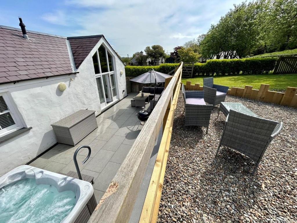 a backyard with a hot tub and some chairs and a table at 3 Bed in Pembroke oc-82584 in Lamphey