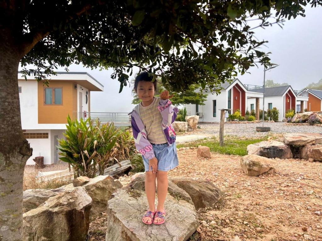 a little girl standing on a rock under a tree at เขาลมเย็น in Khao Kho