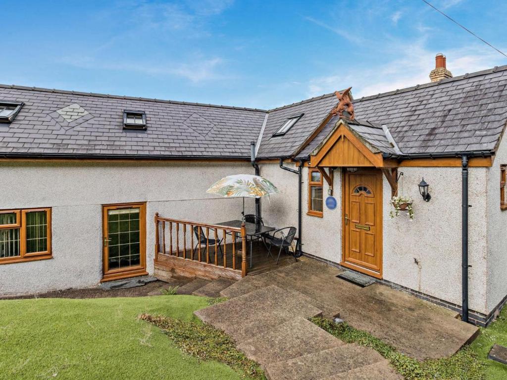 a white house with a wooden door and an umbrella at 2 Bed in Corwen oc-77351 in Corwen