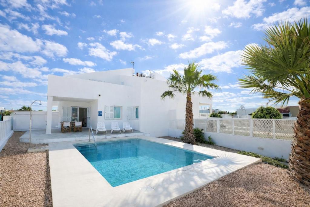a white villa with a swimming pool and palm trees at Villa Son Saura in Cala en Forcat