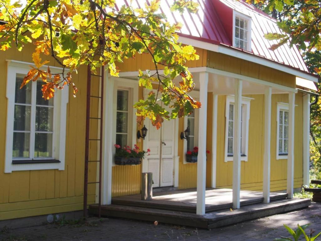 a yellow house with a white door and a porch at Kartanohotelli Artturi in Söderkulla