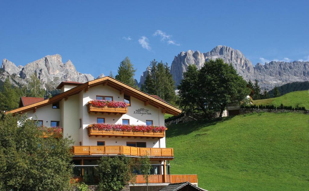 a house with flowers on the balconies on a hill at Residence Rosengarten - Alpenglühen zum Anfassen, inklusive Guestpass in Tires