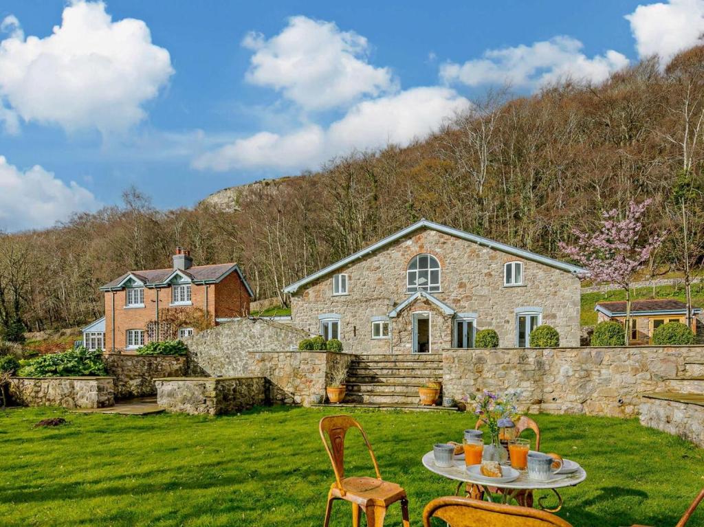 a stone house with a table and chairs in a yard at 6 Bed in Abergele oc-91054 in Llanddulas