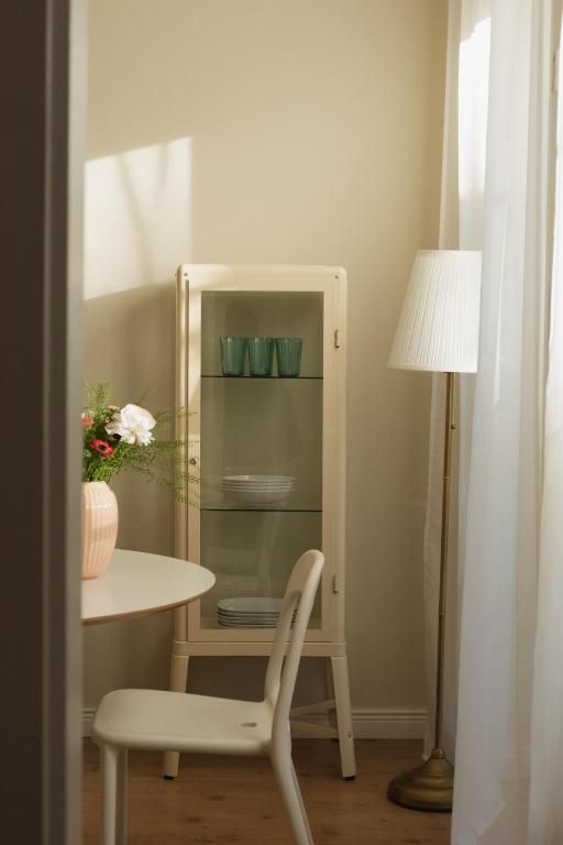 a white cabinet with a table and a chair at JETHON Appartement in der Gasse 2 in Grimschleben