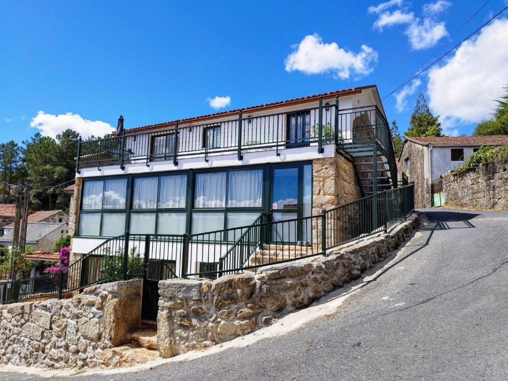 a large house with a balcony on a street at Alojamiento piñeiro arans in Oroso