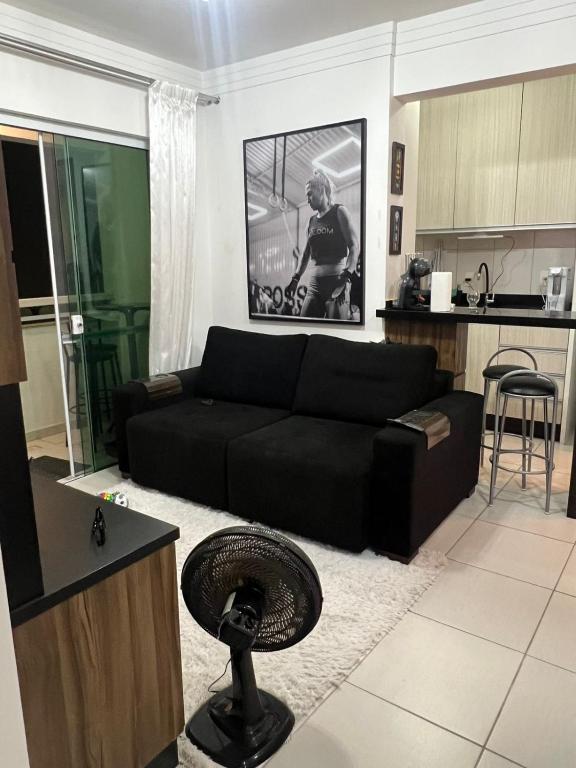 a living room with a black couch and a kitchen at Energia Boa Estadia in Palhoça