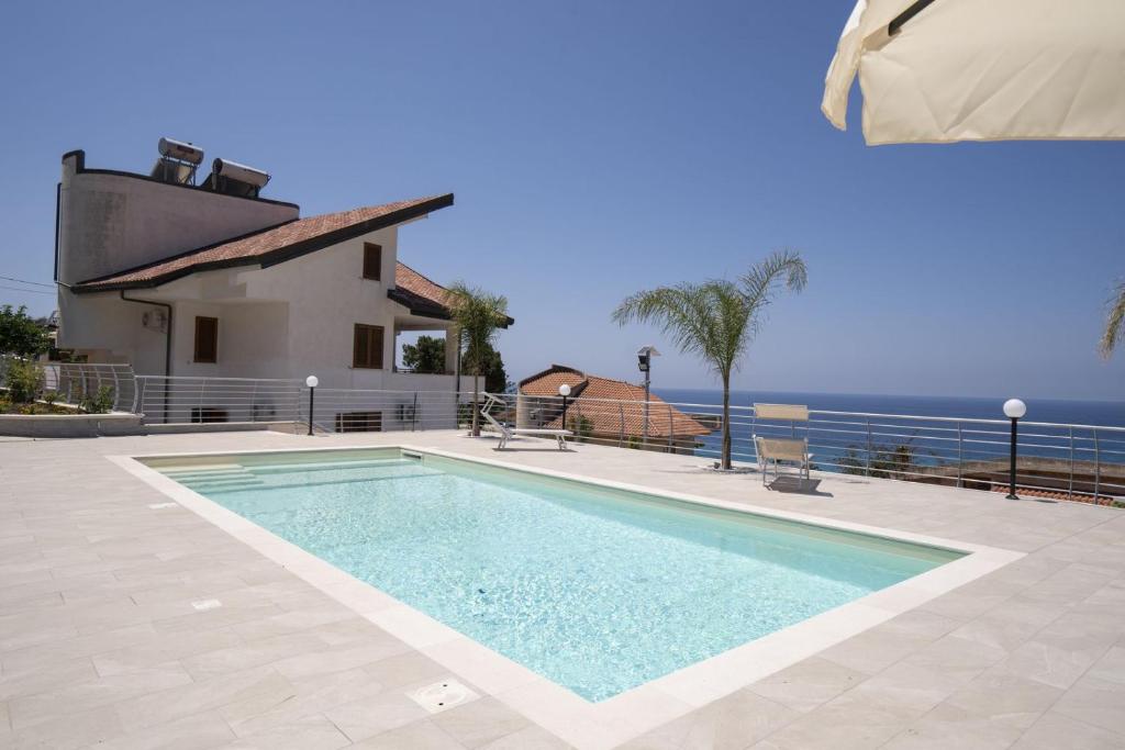 a swimming pool in front of a house with the ocean at Villa Acquamarina, Family apartments with pool - 300 meters from the beach in Santa Maria