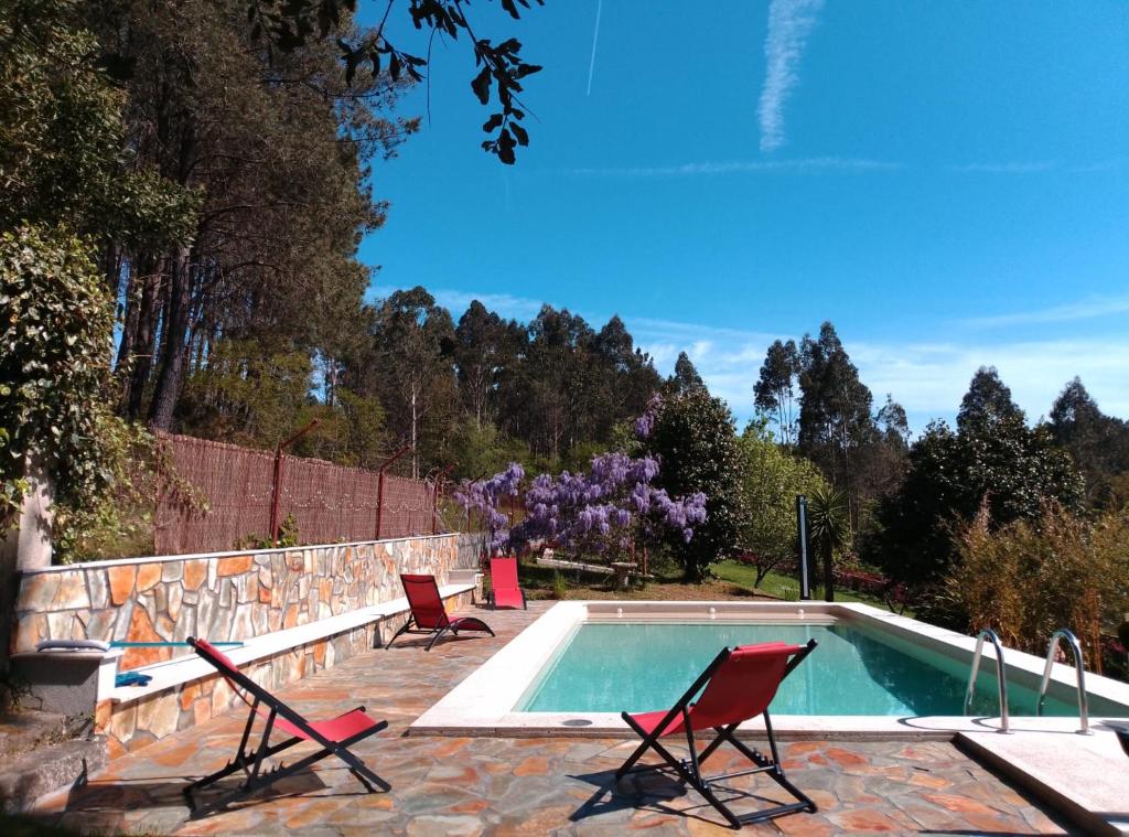 a swimming pool with two lawn chairs and a swimming pool at Casa Quercus Galicia, a 17 minutos de Santiago! in A Estrada