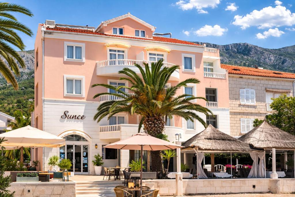 a hotel with a palm tree in front of a building at Villa Sunce Beachfront in Podgora
