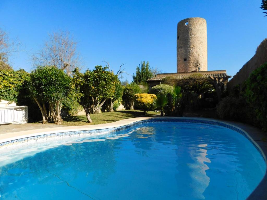 a swimming pool in front of a house with a tower at The Windmill, Garden House in Llubí