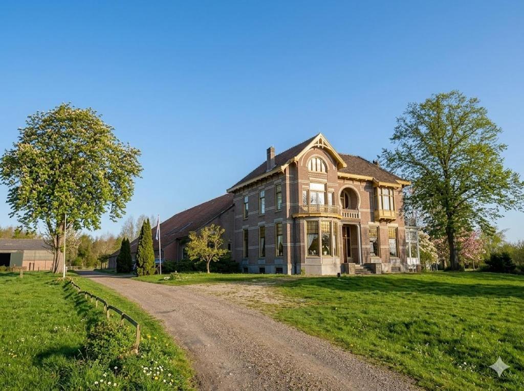 a large house on a field with a dirt road at Boutique Hotel Westerlee in Westerlee