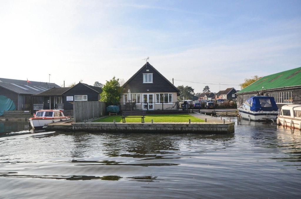 a house on a dock next to a body of water at Kingfisher Lodge in Wroxham