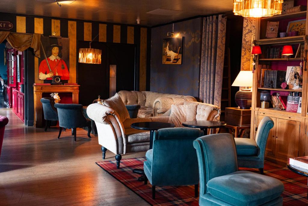 ein Wohnzimmer mit Sofa, Tischen und Stühlen in der Unterkunft Hôtel Le Mercator in Vendôme