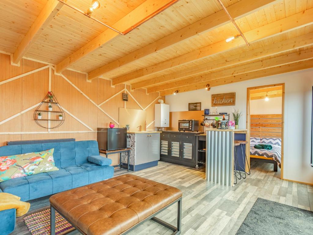 a living room with a blue couch and a kitchen at Holly's Hidden Hideaway - Uk36783 in Sutton Valence