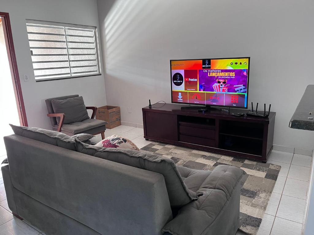 a living room with a couch and a flat screen tv at Casa jardim fonte nova in Goiânia