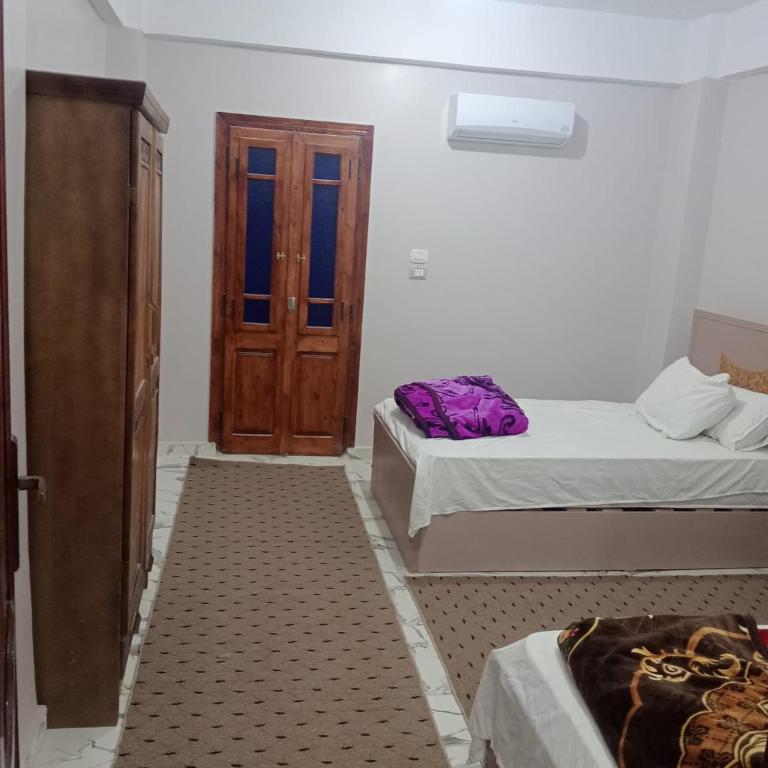 a bedroom with two beds and a wooden door at Dakhly siwa in Siwa