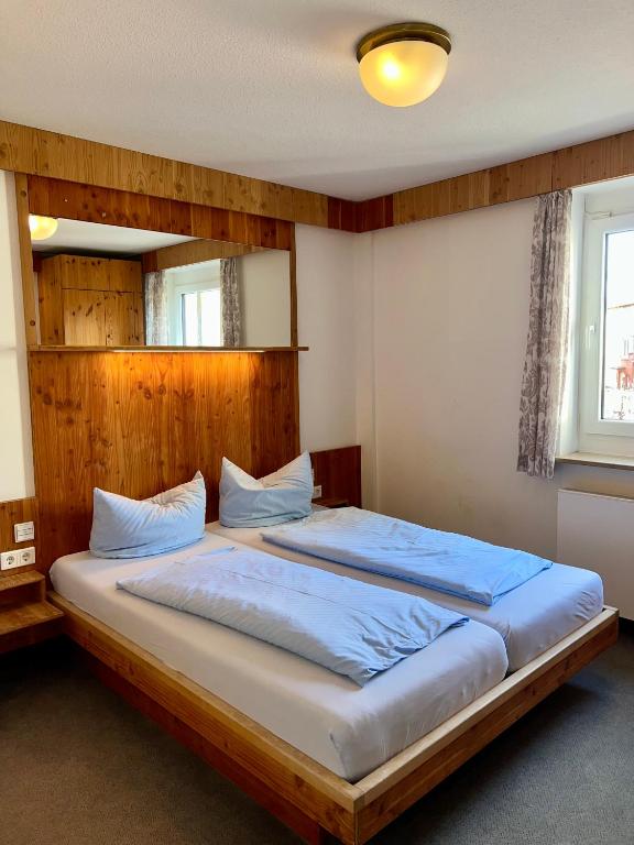 a bedroom with a large bed with a wooden headboard at Hotel Feuerbacher Hof in Stuttgart