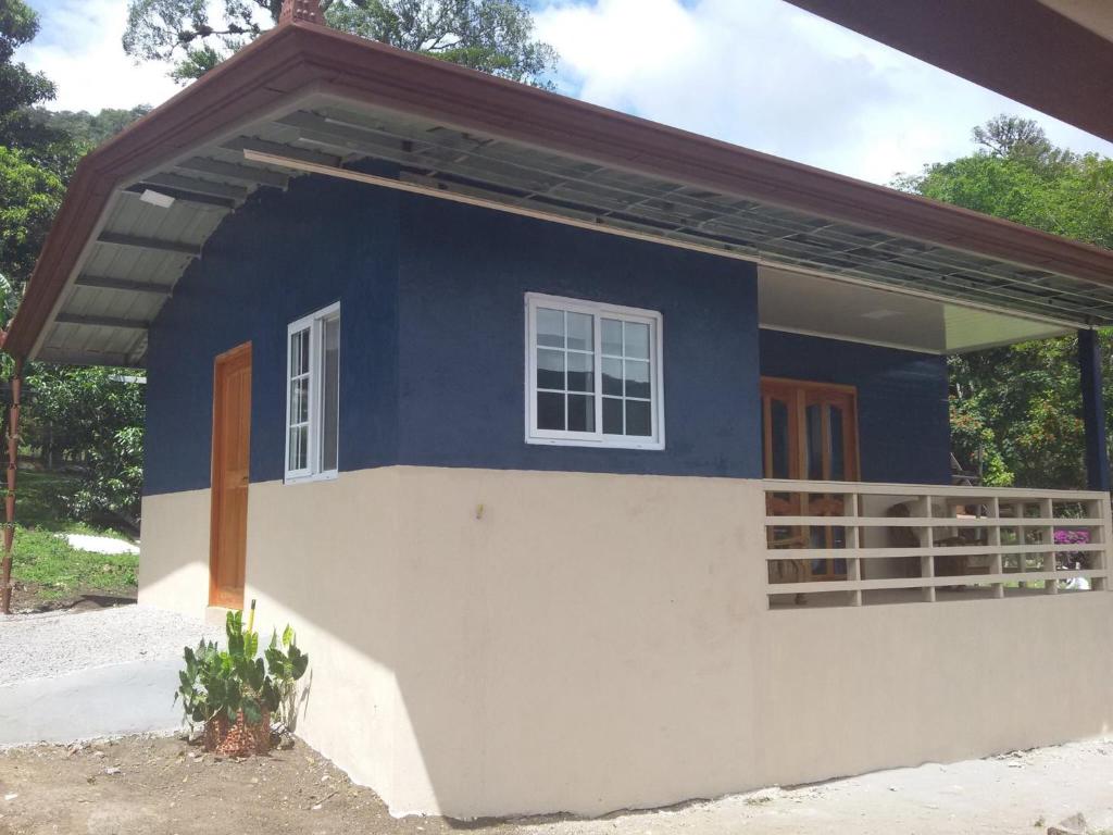 una piccola casa blu e bianca con portico di Hostal Casa Pedro Boquete a Boquete