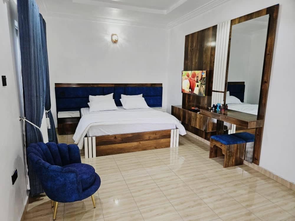 a bedroom with a bed and a mirror and blue chairs at Crystal Bricks Apartments in Port Harcourt
