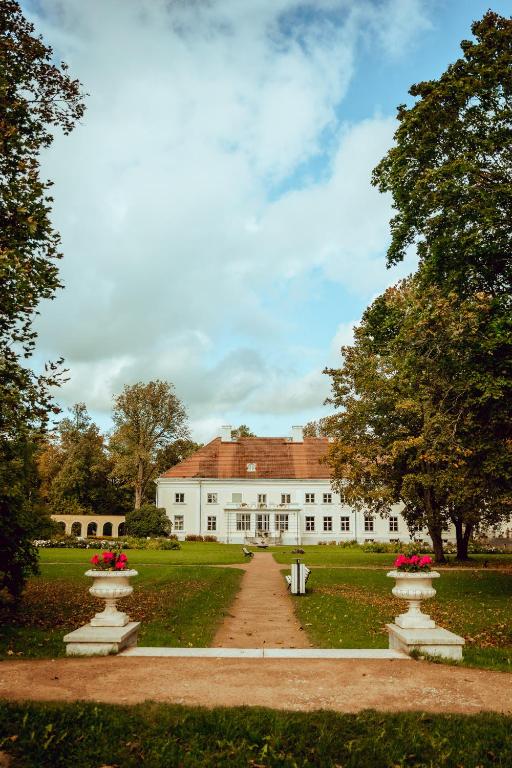 a white house with red flowers in front of it at Anija mõis in Anija
