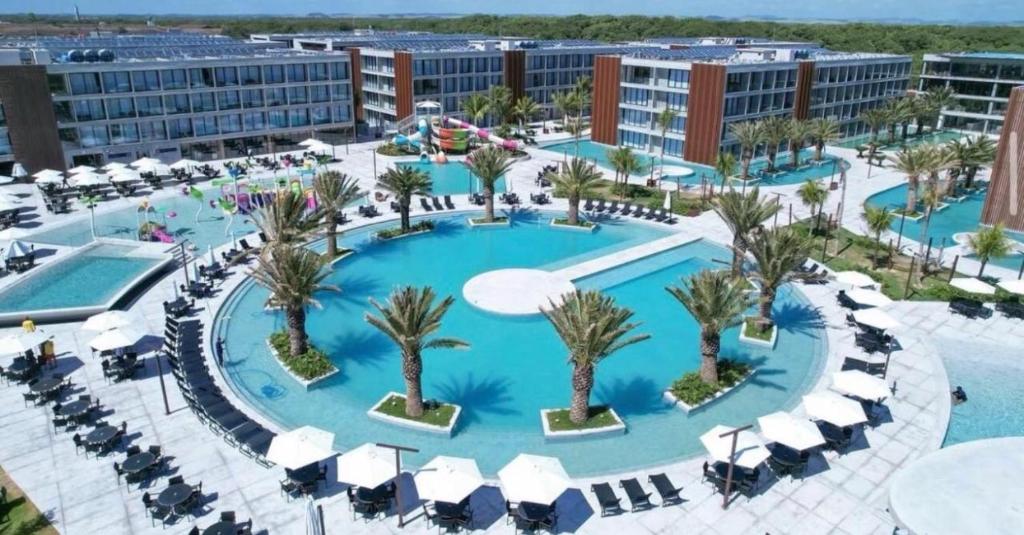 an aerial view of a resort pool with palm trees at Porto2life Máximo 6 pessoas in Porto De Galinhas