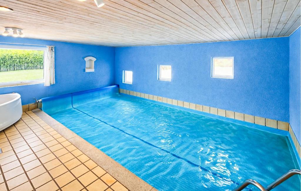 a large swimming pool in a bathroom with blue walls at Nice Home In Oksbøl With Sauna in Oksbøl