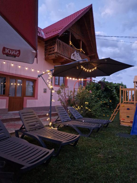 a group of chairs and an umbrella in front of a building at Cabana Apus de Soare in Râșca