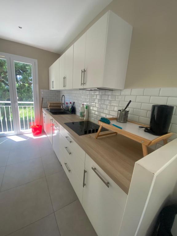 a kitchen with white cabinets and a wooden counter top at Maison luxueuse proche de Paris centre in Aulnay-sous-Bois
