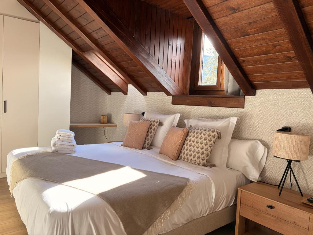 a bedroom with a large white bed with wooden ceilings at Apartamentos St.Anton Suites Benasque in Benasque
