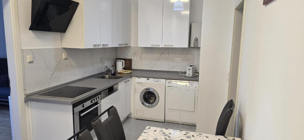 a kitchen with white cabinets and a washer and dryer at Monteur und Messewohnung in Rodgau