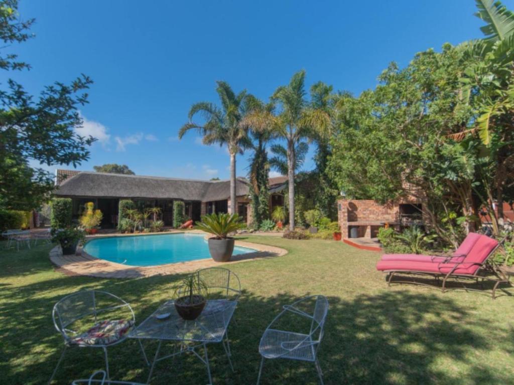 a yard with a pool and chairs and a house at Amani Guest Lodge in Port Elizabeth