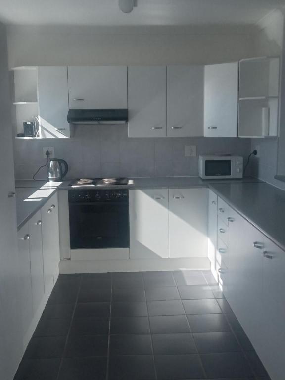 a white kitchen with white cabinets and a stove at white house Bluewaterbay in Gqeberha
