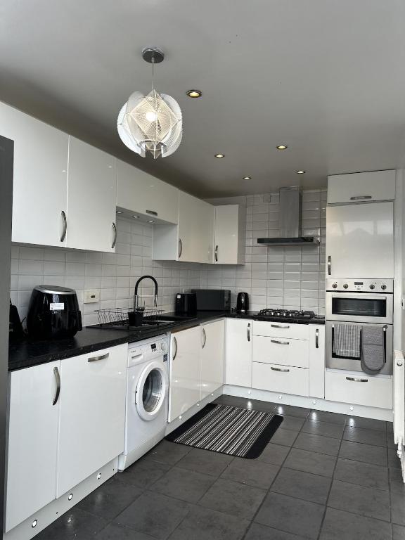 a kitchen with white cabinets and a washer and dryer at New Haven Atherton Greater Manchester in Atherton