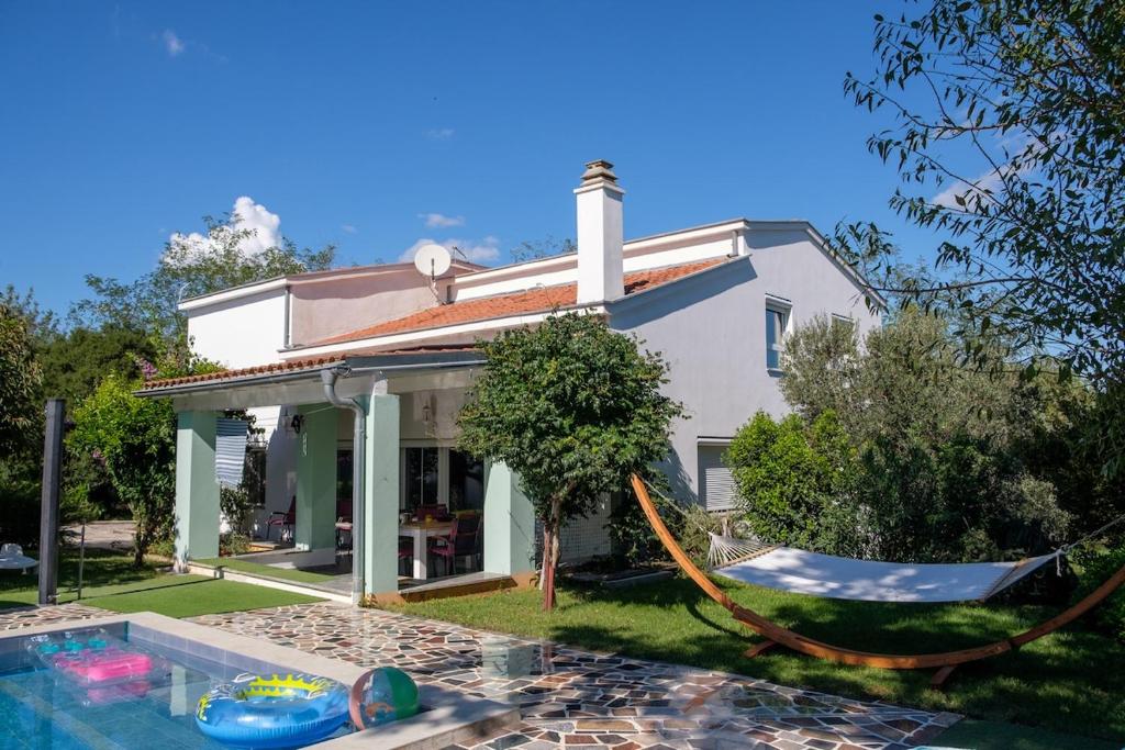 a house with a hammock next to a swimming pool at Villa Vinko in Donje Raštane