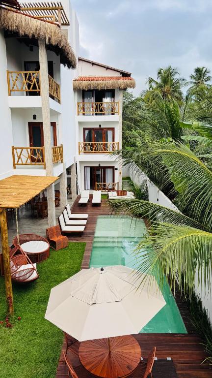 an external view of a hotel with a pool and an umbrella at Vila Marina Icaraizinho in Icaraí