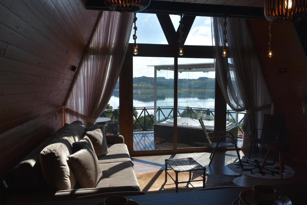 a living room with a couch and a large window at Cabanas Lago - Piratuba-SC in Piratuba