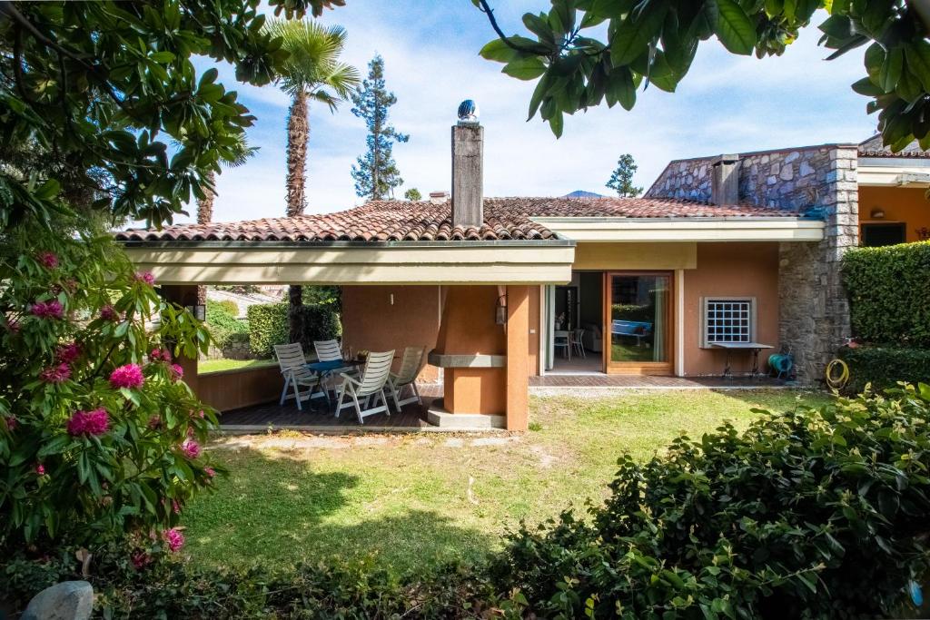 a house with a patio and a yard at Parco Hermitage - Vila Camelia in Porto Valtravaglia