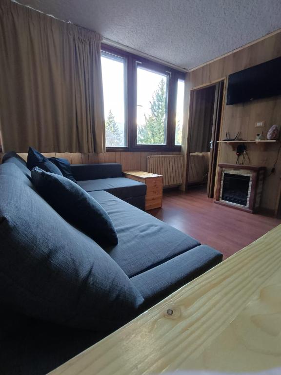 a living room with two blue beds and a fireplace at Marilleva 1400 - Alpine Apartment in Marilleva