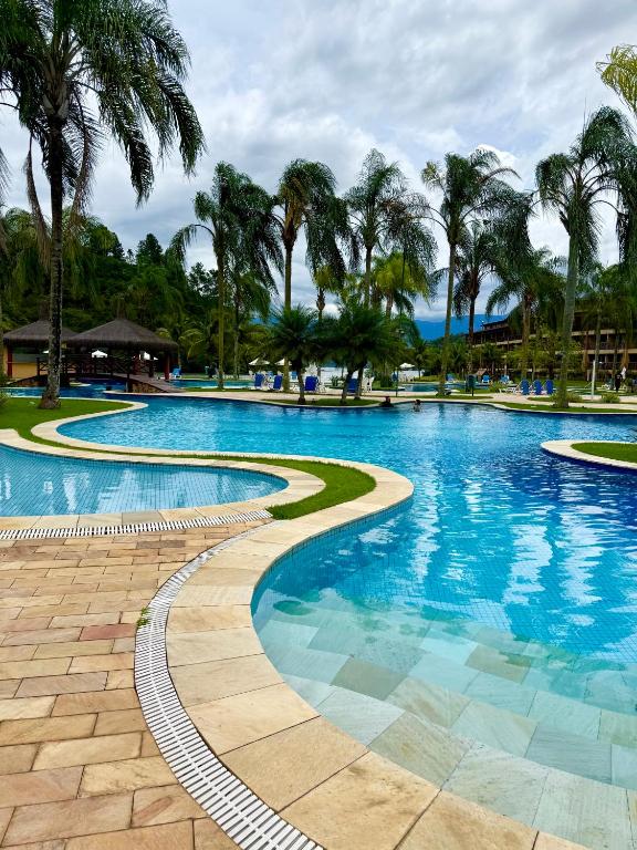 a swimming pool with palm trees in a resort at Chalé Mar e Sol, Marina e Resort Angra in Angra dos Reis