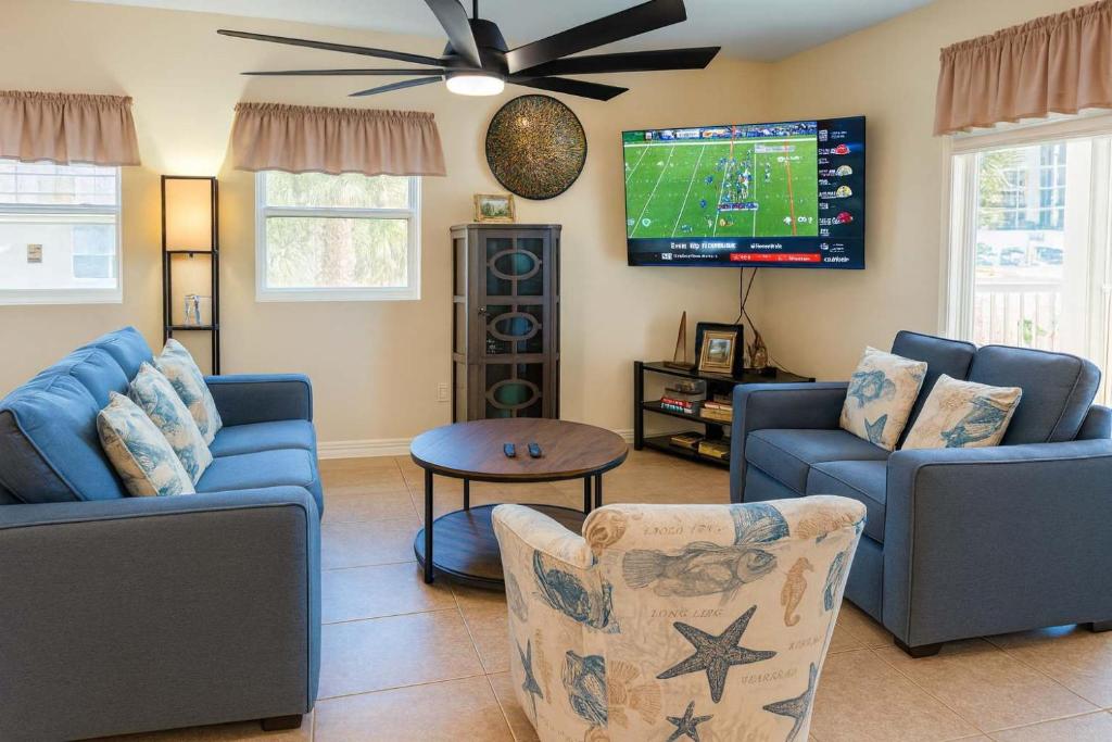a living room with two blue couches and a tv at Pompano Beachview Home home in South Padre Island