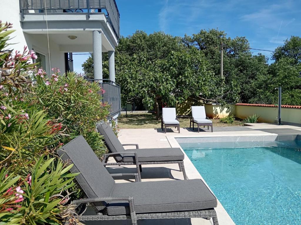 a pool with two lounge chairs next to at Apolo Apartments - Pool & Garden Retreat in Pula