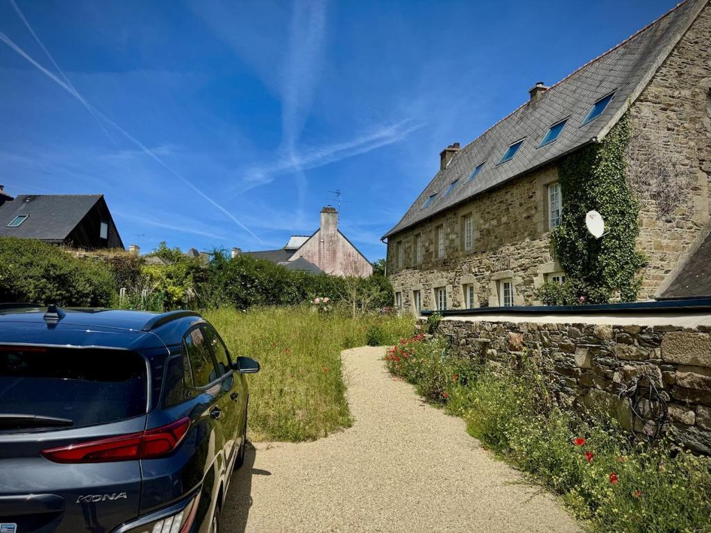 a car parked on a path next to a stone building at Charming house in an old rectory PMR in Tréguier