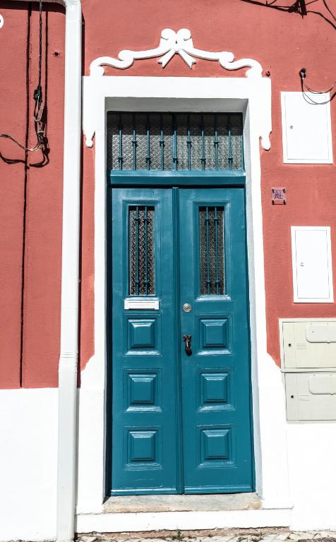 a blue door on a red and white building at Republica House in Trafaria