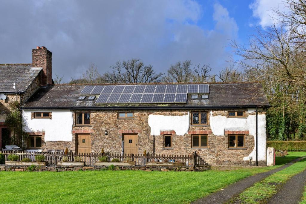 an old stone house with solar panels on the roof at Finest Retreats - Oak Leaf Cottage in Beaworthy