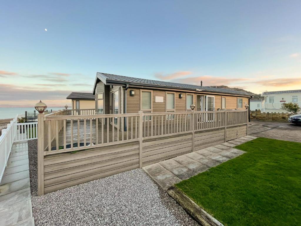 a house with a wooden fence and a yard at Sunset Lodge in Llanddulas