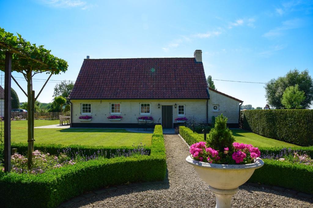 Casa blanca con techo rojo y jardín en Cottage Nostalgia, en Damme