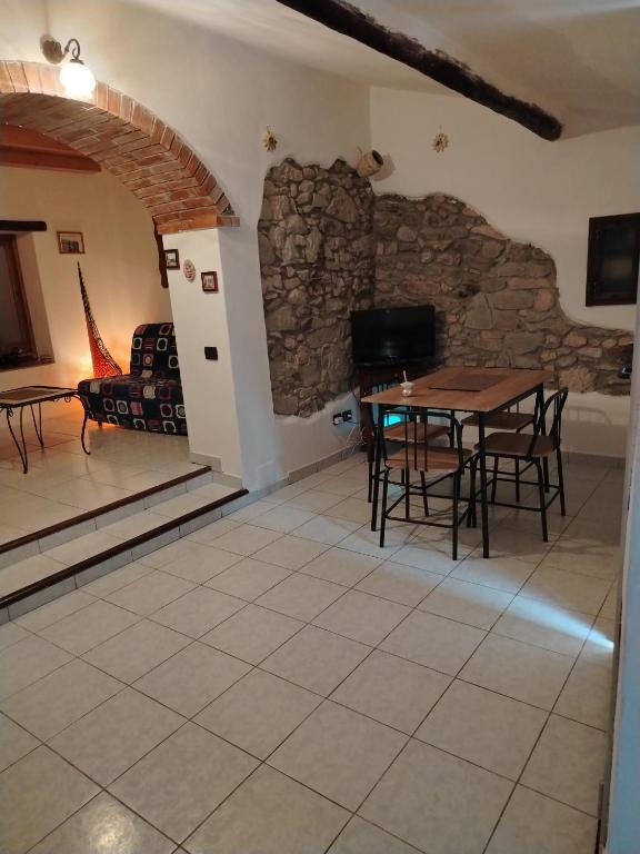 a living room with a table and a stone wall at La maison d'amour in Sanluri